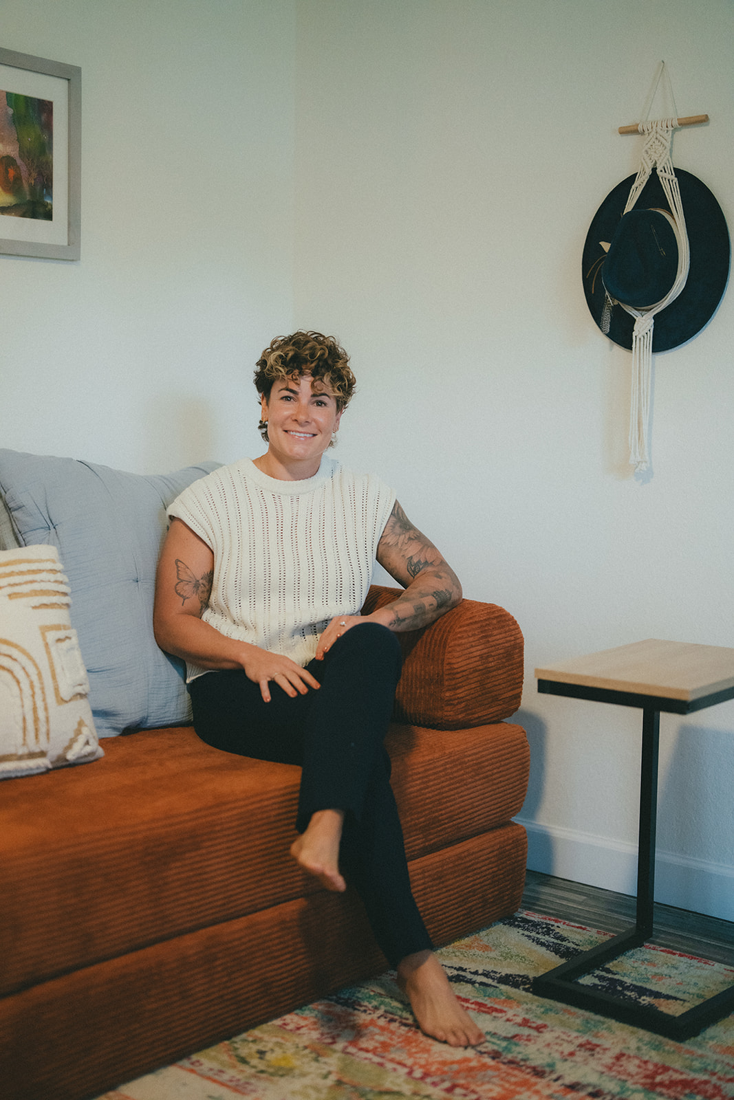Brittany DelleChiaie, founder of GATI Passage, seated on a rust-colored sofa